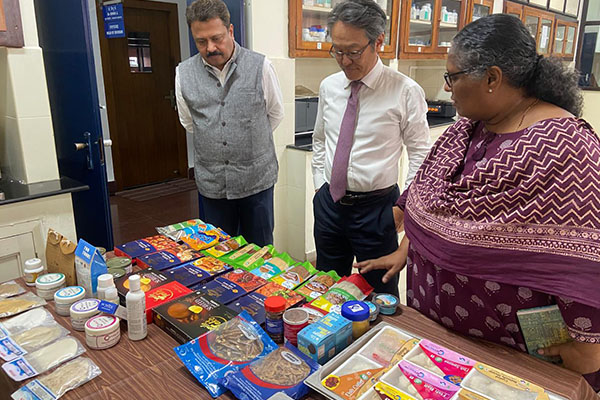 A woman explains about products displayed on a table to two men.