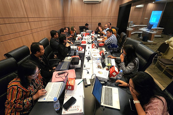People working on their laptops around a long table.