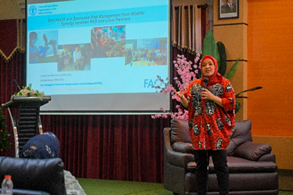 Woman with hijab talking in front of a screen projector