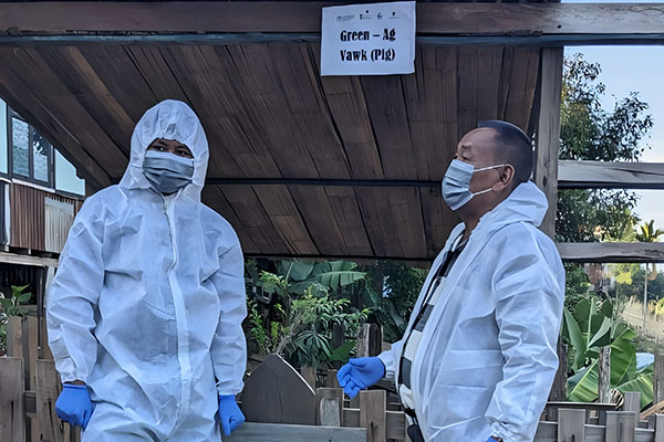 Two men wearing personal protective equipment and masks.