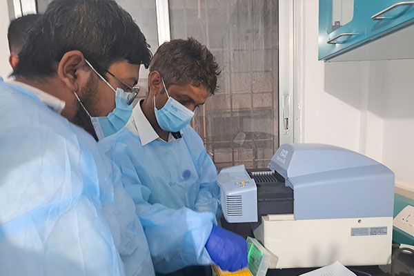People in PPE working on a lab equipment